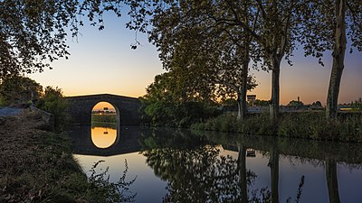 'n Brug word in die Canal du Midi in Villeneuve-lès-Béziers, Frankryk, weerkaats.