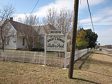 White painted house behind a sign announcing the Robert E. Howard Museum