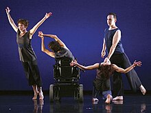 four members of the dance company with elegant arms during a performance on stage with a blue background