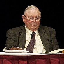 Munger seated, wearing a suit