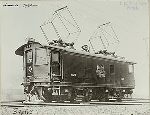 Boxy locomotive with two pantographs raised to contact overhead lines