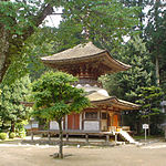 A two-storied pagoda shaped tower with a square base and a round upper story. The walls are faded white and the beams faded red.