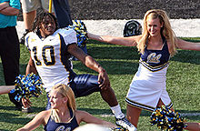 Lynch, s'étirant, une main sur le genou, à gauche d'une cheerleader de l'université de Californie.
