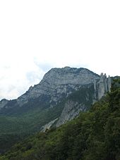 Parois et dalles rocheuses verticales surplombant des versants boisés.