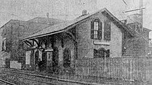 A two-story wooden railway station in an urban area