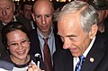 Ron Paul signing an autograph as campaign staff look on.