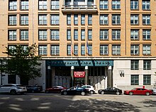 A view of the steel-and-glass main entrance to Stuyvesant High School. There is a sign above the entrance with the school's name in large capital letters.