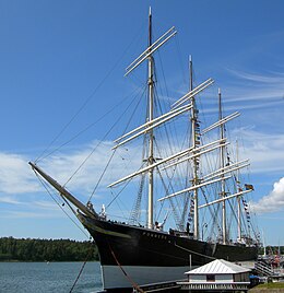 Een groot viermaster zeilschip zonder zeilen, liggend aan de kade