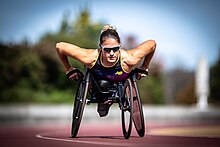 White woman with a red and white top in a black wheelchair.