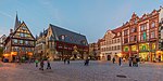 A town square with two visible buildings and a few tourists.