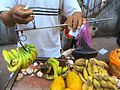 天秤ばかりの棒（天秤棒）と分銅を調整してバナナの重さを量る果物売り／中国海南省。