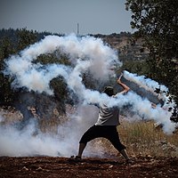 Un manifestant utilitza una fona per enviar una granada de gas lacrimògena cap a les soldats israelians durant una protesta setmanal del palestí a Ni'lin , juliol de 2014