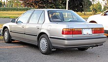 Rear three-quarter view of a four-door car with a three-box body style.