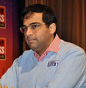 A photograph of a man playing chess with blue sweater.