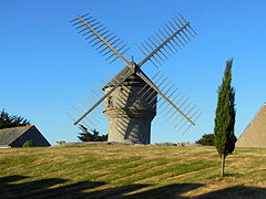 Photographie d’un moulin en pierre, équipé d’ailes à toiles.