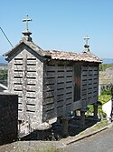 A Latin cross and a high cross atop a Galician hórreo (granary)