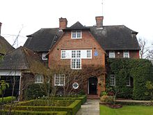 A substantial detached Edwardian-era red-brick house with gabled central bay with steeply pitched tiled roofs each side.