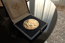 Photographie d'une médaille d'or des Jeux olympiques, dans un écrin noir.