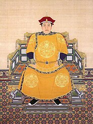 A painted image of the head and chest of a black-haired man with droopy eyes wearing a white-edged two-tiered red cap and a bright yellow garment whose lapels are decorated with five-clawed yellow dragons against a blue background with clouds and vegetation.
