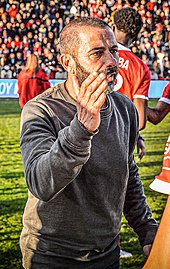 Photographie de profil de Nicolas Usaï levant le bras droit lors d'une fin de rencontre de football.