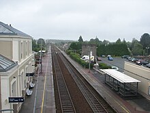 L'intérieur de la gare vu de la passerelle, avec le bâtiment voyageurs, les deux voies et les deux quais