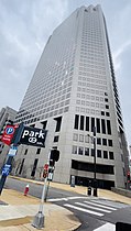 A tall, thin building with small windows is nestled between two other buildings.