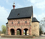 A stand-alone gatehouse surrounded by many trees.
