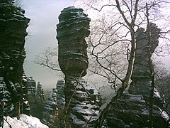 Dos pilates de piedra estratificada parcialmente cubiertos en nieve. Montes d'Arenisca del Elba, Alemaña.