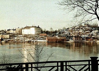 En vy från Långholmen över Riddarfjärden mot Marieberg på Kungsholmen visar ett stadslandskap i förändring. På bilden från 1926 syns i mitten en hög, vit byggnad: Mariebergs porslinsfabrik och nere vid stranden Triewalds malmgård omgiven av flera byggnader. På bilden från 2010 syns en ny siluett: DN-skrapan och SvD-huset från 1960-talet och höga bostadshus. Där porslinsfabriken fanns är numera byggnaden för Rysslands ambassad i Stockholm och Tierwalds Malmgård ligger ensamt vid stranden. Fotografiet från 1926 är taget av Gustaf W. Cronquist på en autochromplåt.