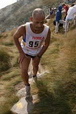 Un coureur montant un sentier, les mains posées sur les cuisses.