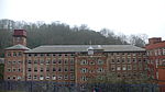 A large building with many windows behind a blue fence.