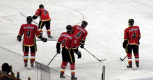 View from behind of five hockey players, each wearing red uniforms with black trim. The back of all five players reads "MCCRIMMON 4".