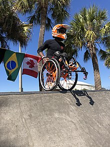 Wheelchair skater Delmace Mayo balancing on his wheels on top of a skate ramp