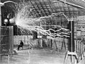 26. Nikola Tesla szerb-amerikai feltaláló híres fényképe a Colorado Springs-i laboratóriumából 1899 decemberéből, amikor állítólag a Tesla-tekercs nagyfeszültségű generátora mellett ülve olvasott a hatalmas elektromos kisülés közben. A kép Dickenson V. Alley fényképész kettős expozícióval készült promóciós munkája (javítás)/(csere)