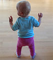 Bebê usando membros superiores para se equilibrar, enquanto utiliza os membros inferiores para andar.