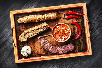 Ajvar, pocházející ze srbské a makedonské kuchyně, s bagetou, česnekem, chilli papričkami a salámem