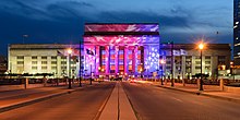 A large neoclassical building lit up red and blue with white stars.