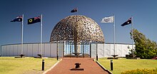 Colour photograph of a memorial structure with flags in front of it