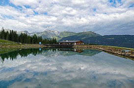 Bergeralm (de), avec sa réserve d'eau pour les canons à neige et un restaurant à l'arrière plan, à Steinach am Brenner. Aout 2021.