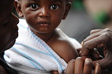Na widza patrzy zaskoczone dziecko, które przyjmuje szczepionkę