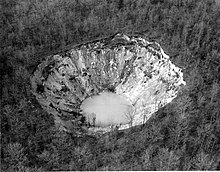 More than three acres of trees are missing in a forest after collapsing into a funnel shaped pit with water at the bottom.