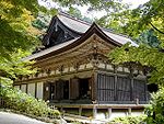 Wooden building with hip-and-gable roof, white walls and light colored wooden beams.