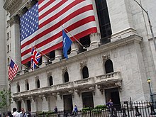 A big flag is stretched over Roman style columns on the front of a large building.