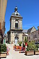 Tour-clocher d'une église au bout d'une rue pavée.