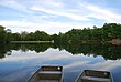 A lake with green trees in the background reflecting upon the water.