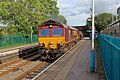 An EWS Class 66, running north through the station, with a freight train.