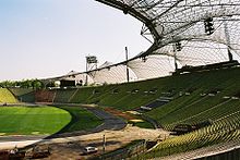 Photographie d'un stade de football. Les tribunes à droite, la pelouse à gauche.