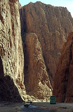 Deep gorge photographed from bottom, with car and bus