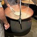 After acetic acid is added, cheese curds form and are removed with a wooden pail.