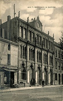 Photographie en noir et blanc d'un grand bâtiment en pierre de 4 étages.